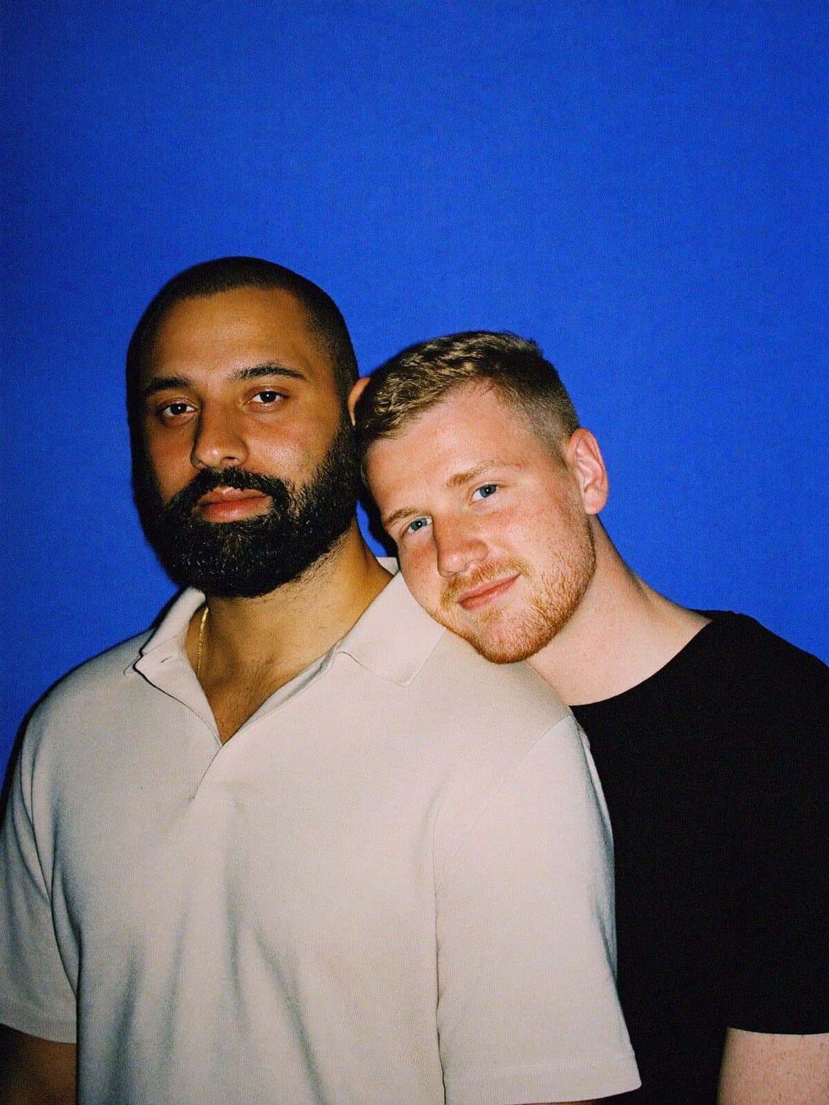 A couple leaning into each other against a cobalt blue backdrop